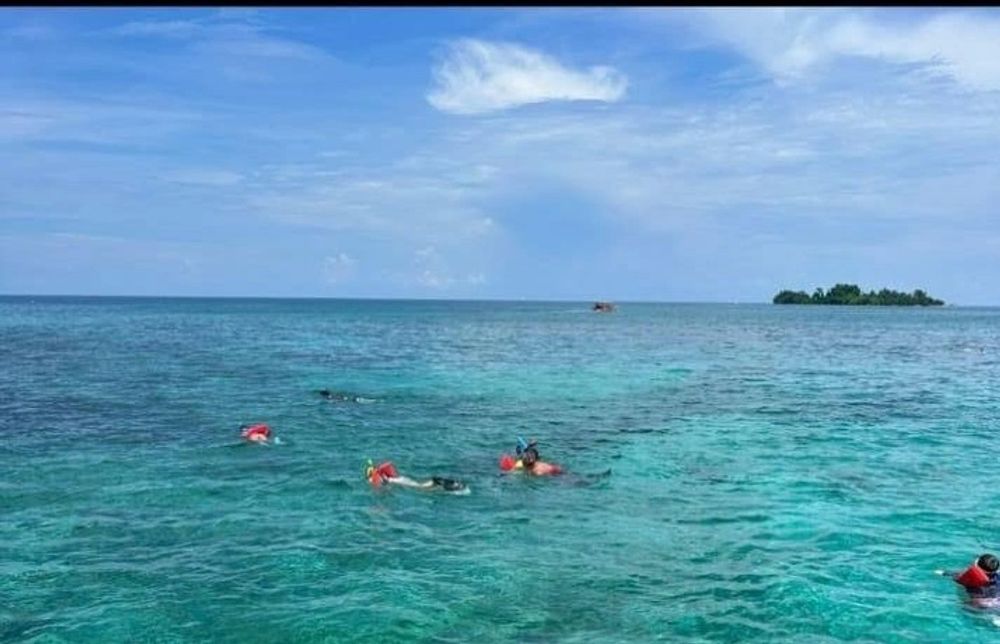 Boat bow pointing toward a green island across the sea